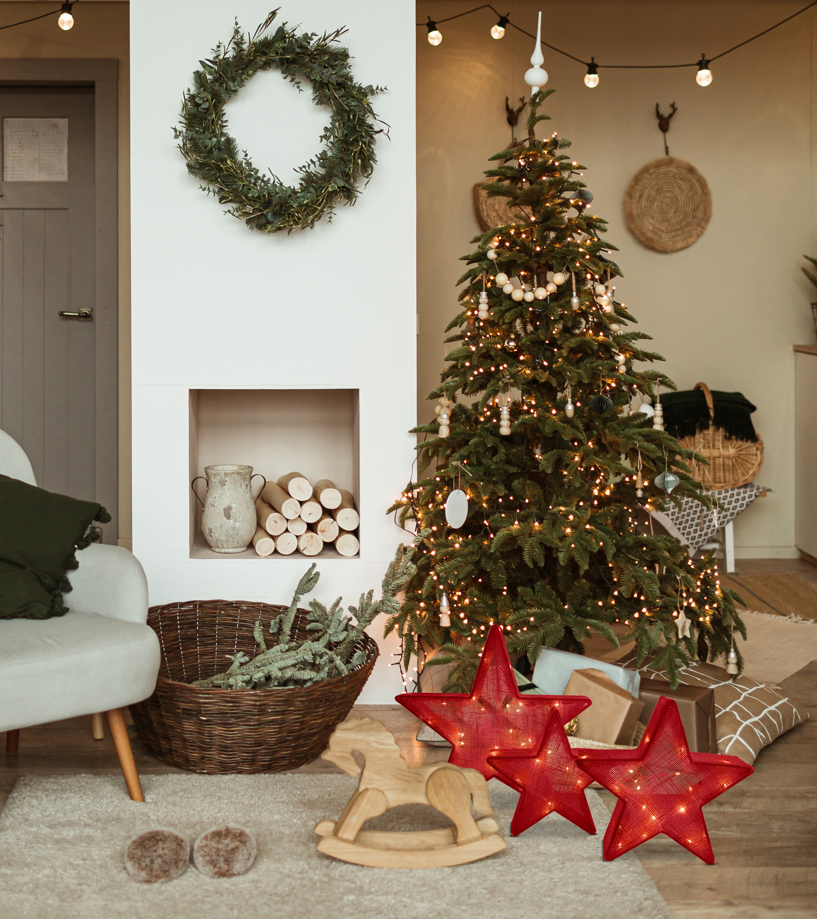 Weihnachtsszene mit geschmücktem Baum, Kranz, Sternen und einem Schaukelpferd.