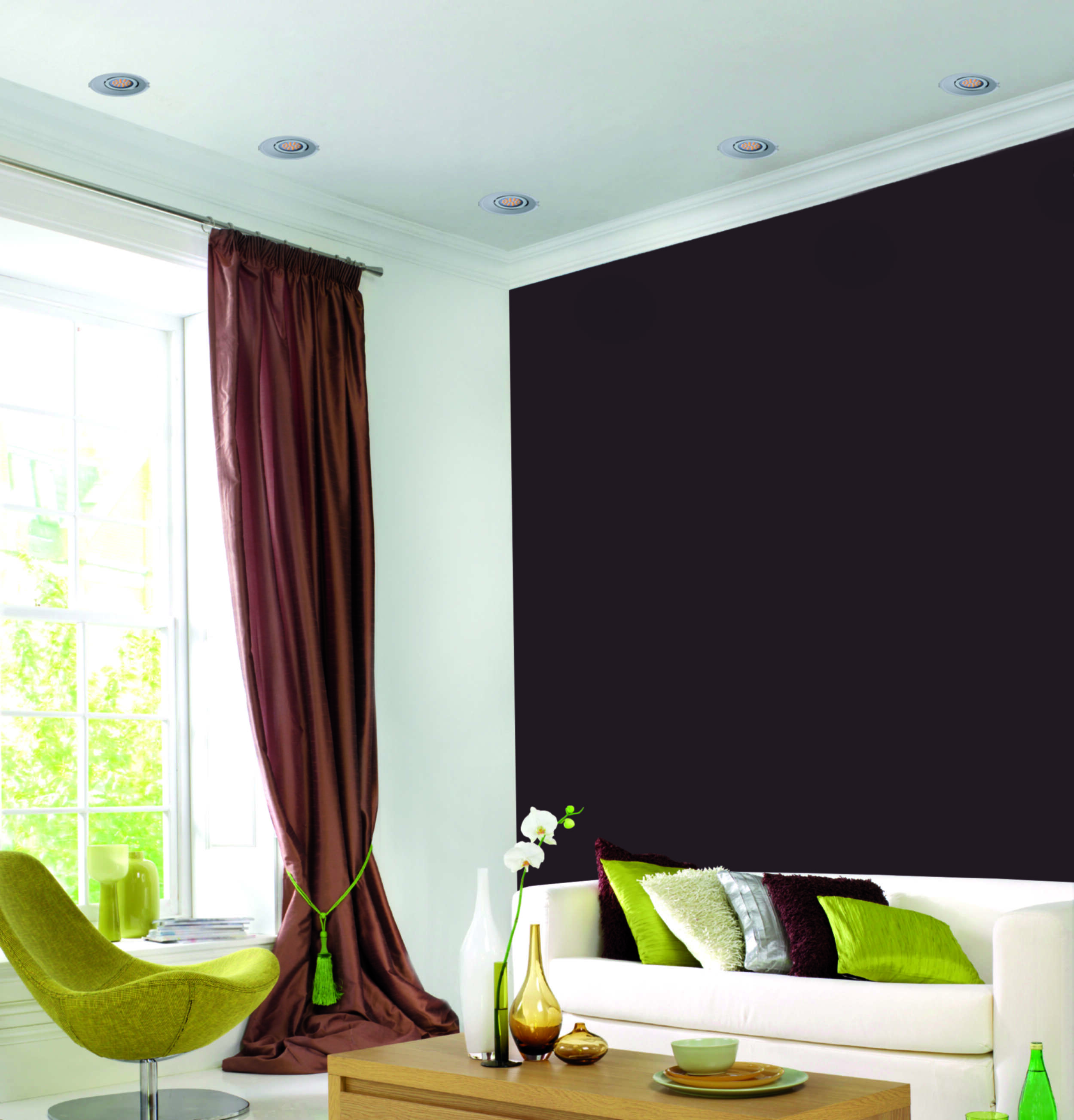 Ein Raum mit weißem Sofa, braunen Vorhängen und einer dunkelbraunen Wand.
