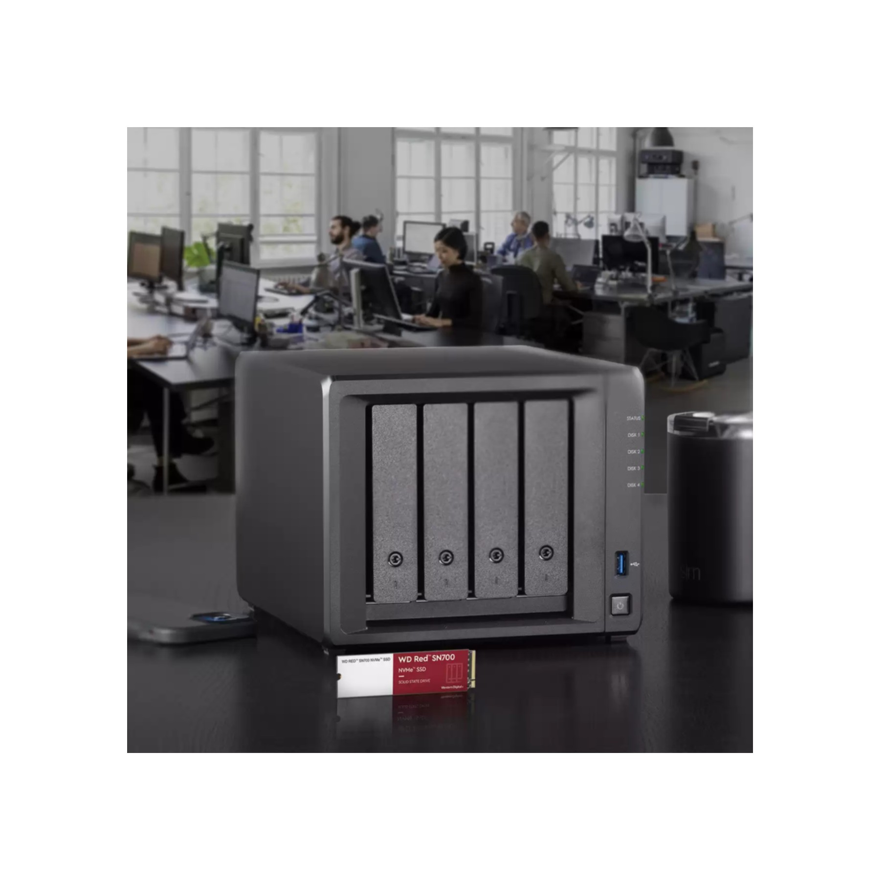 Czarne urządzenie z włożonym czerwonym dyskiem SSD, z ludźmi w tle.