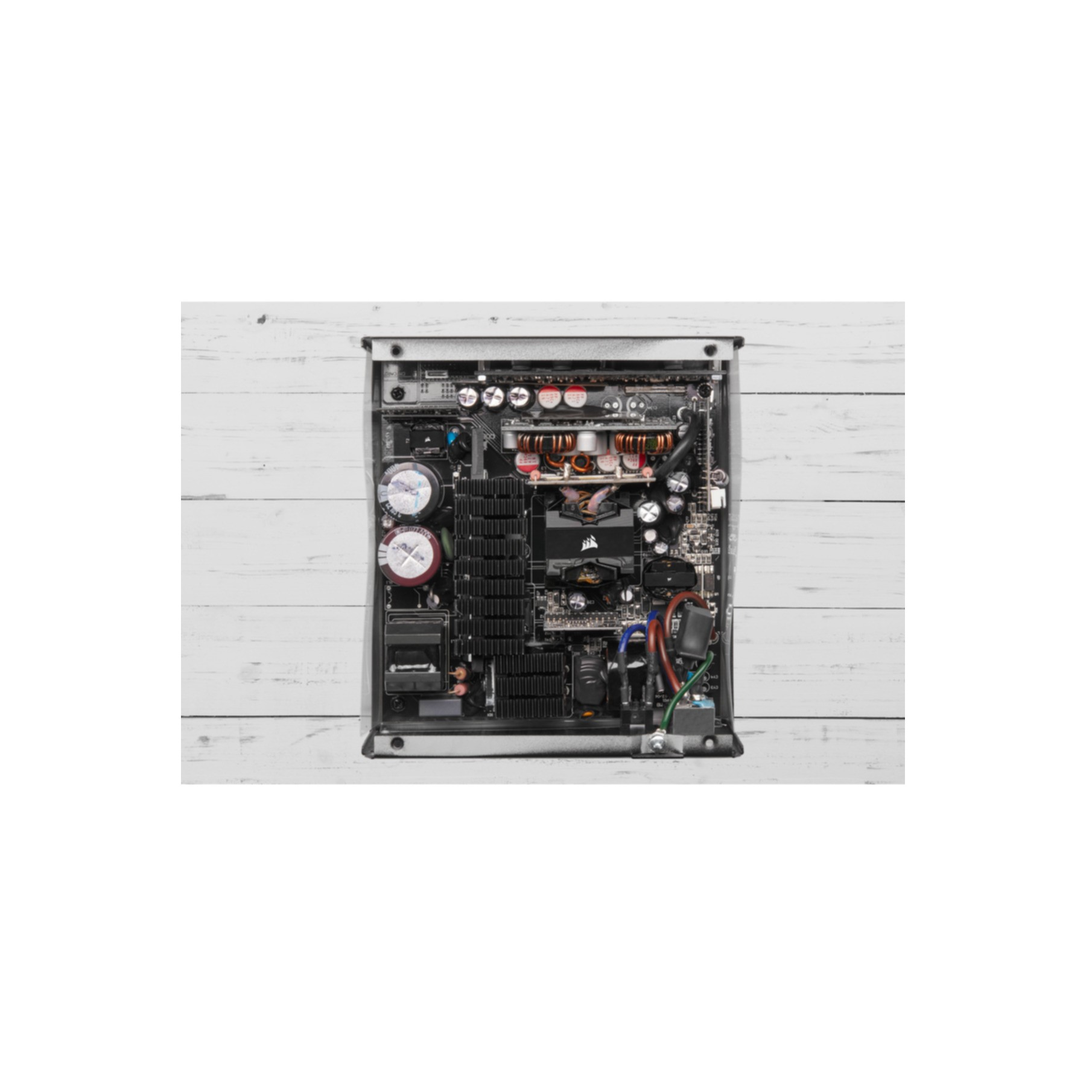 Una vista interna di un alimentatore per computer, che mostra vari componenti e circuiti. Lo sfondo è bianco.