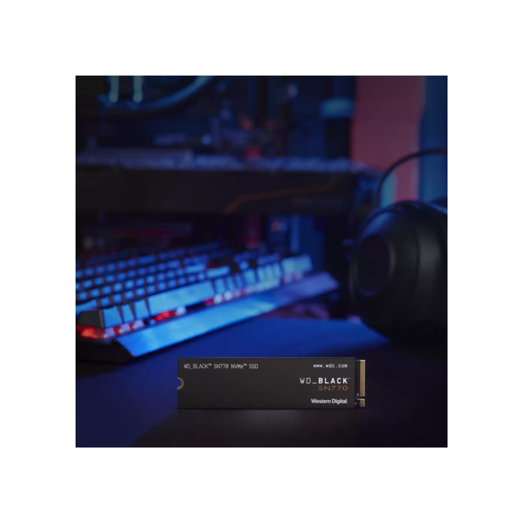 Dysk SSD na biurku z klawiaturą i słuchawkami w tle. Światła są kolorowe.