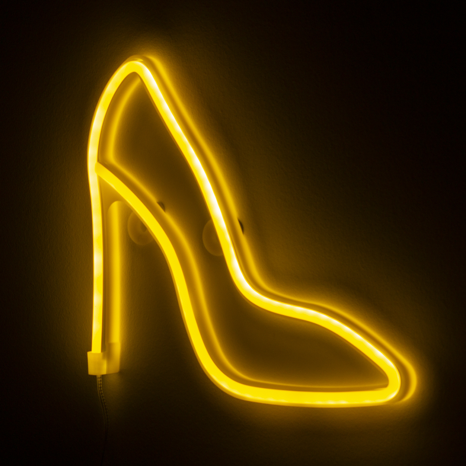 Letrero de neón de un zapato de tacón alto. Luz amarilla sobre fondo negro. Montado en la pared.