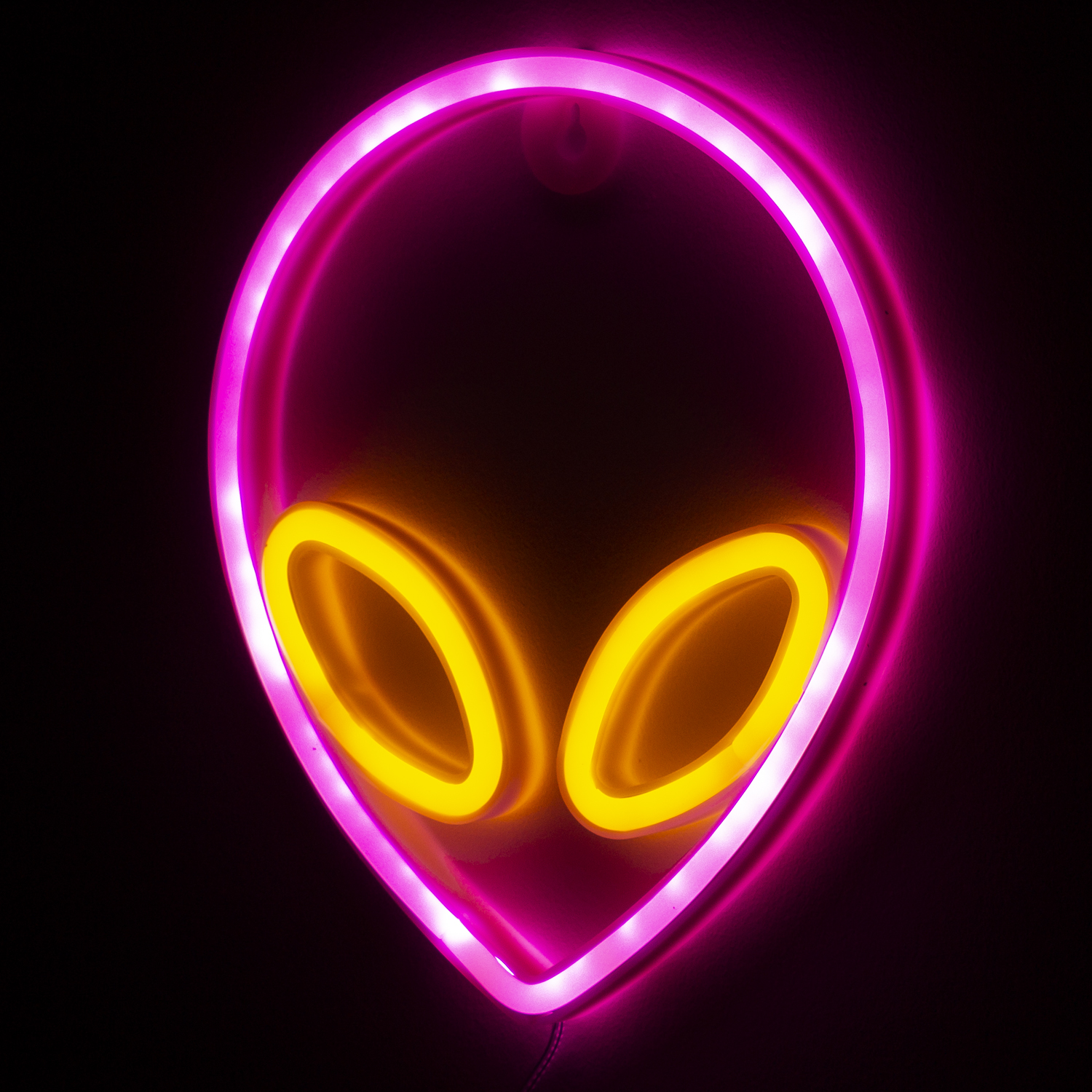 Insegna al neon aliena. Contorno rosa e occhi gialli. Sfondo nero. Montato su un muro.