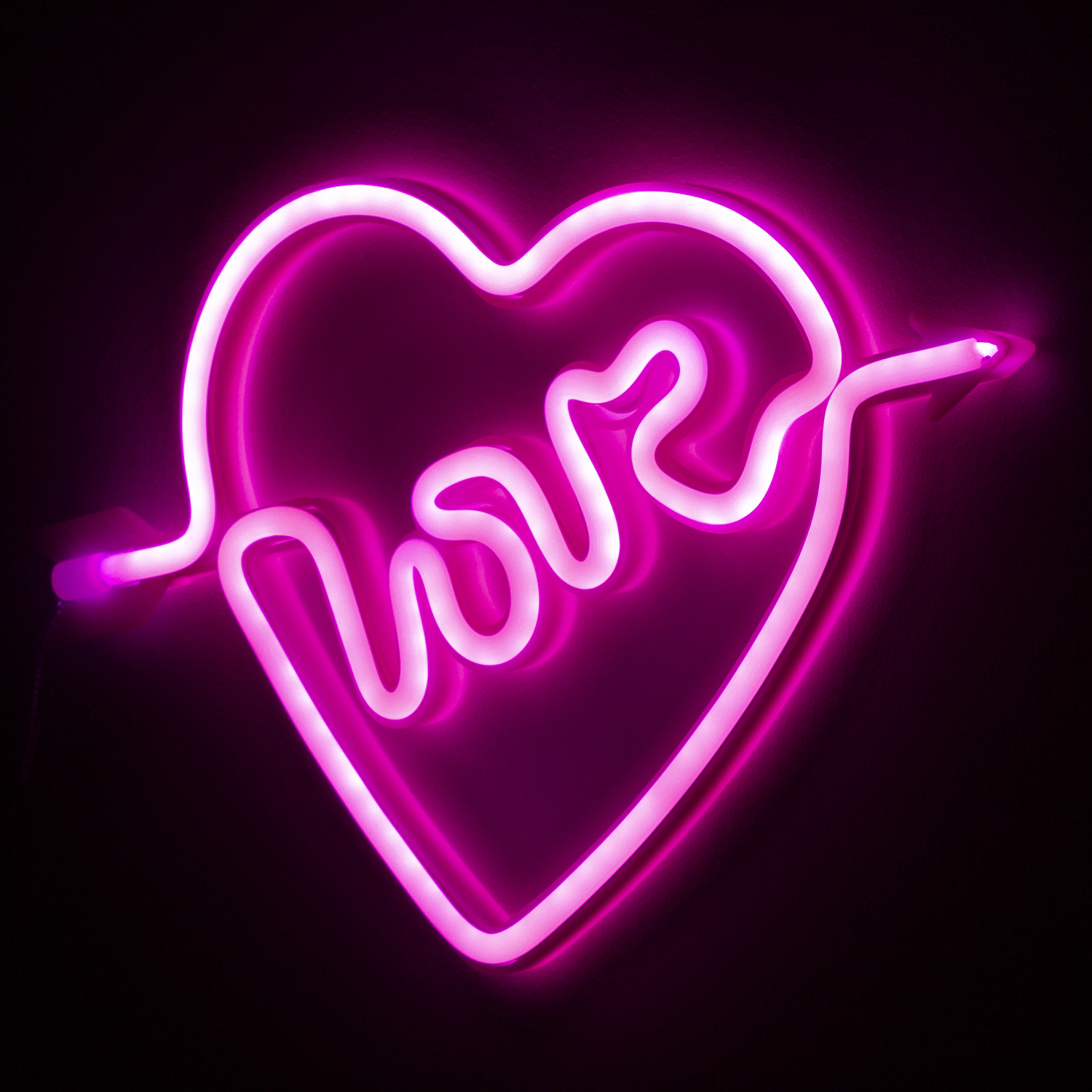 Cuore neon rosa con la parola 'amore' in corsivo, con una freccia.