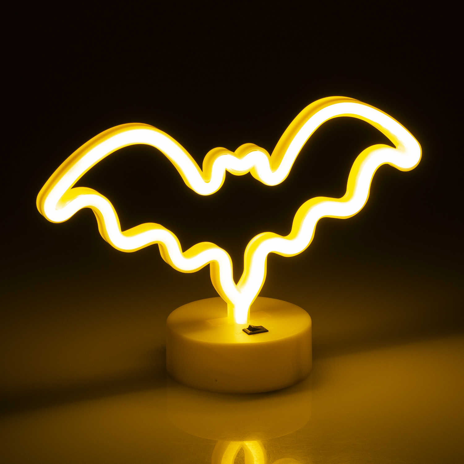 Una luce al neon gialla a forma di pipistrello su una base gialla.