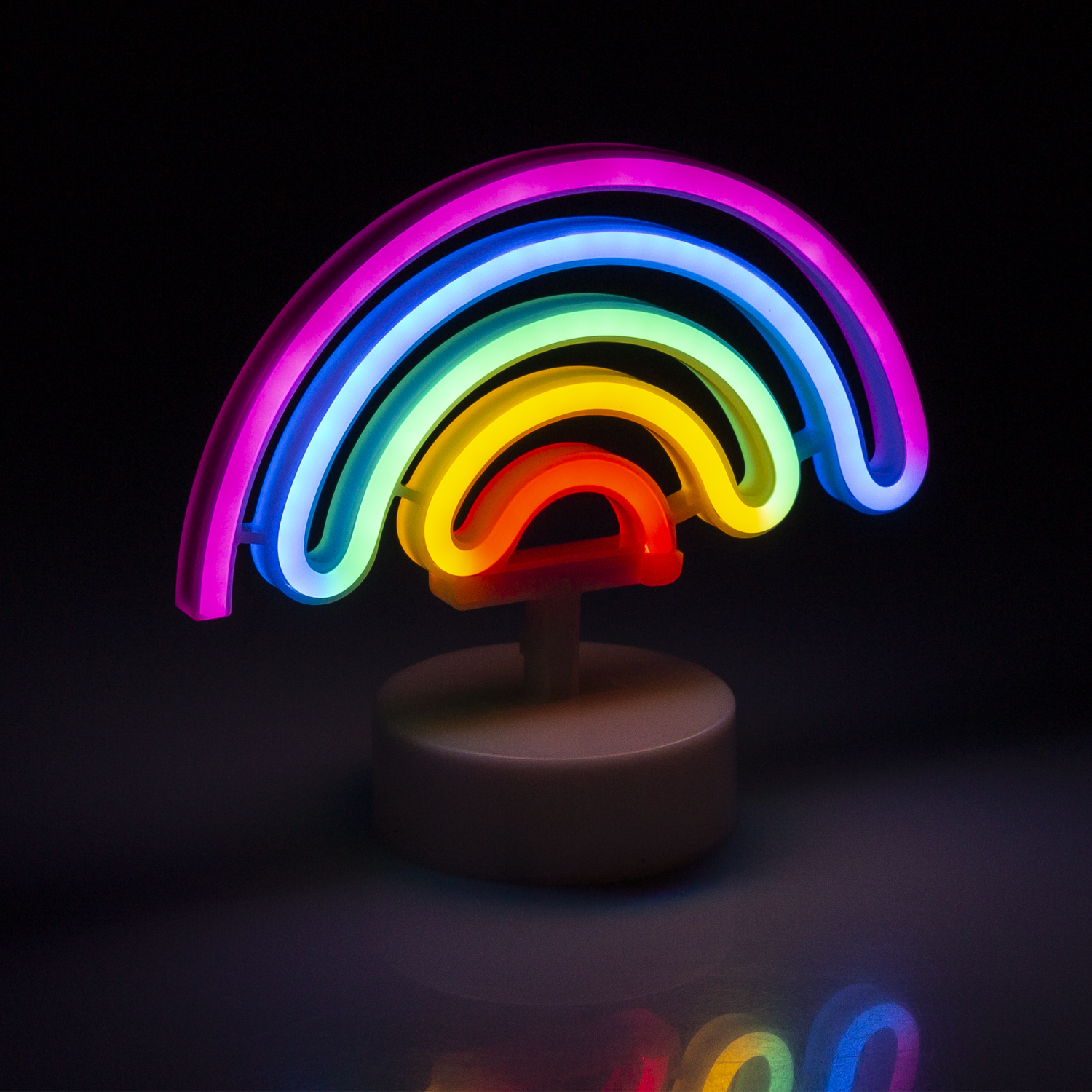 Una luce al neon arcobaleno su un supporto bianco, su sfondo nero. L'arcobaleno è multicolore.