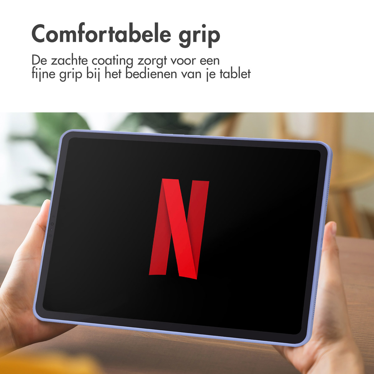 Een persoon houdt een tablet vast met het Netflix-logo op een zwart scherm.