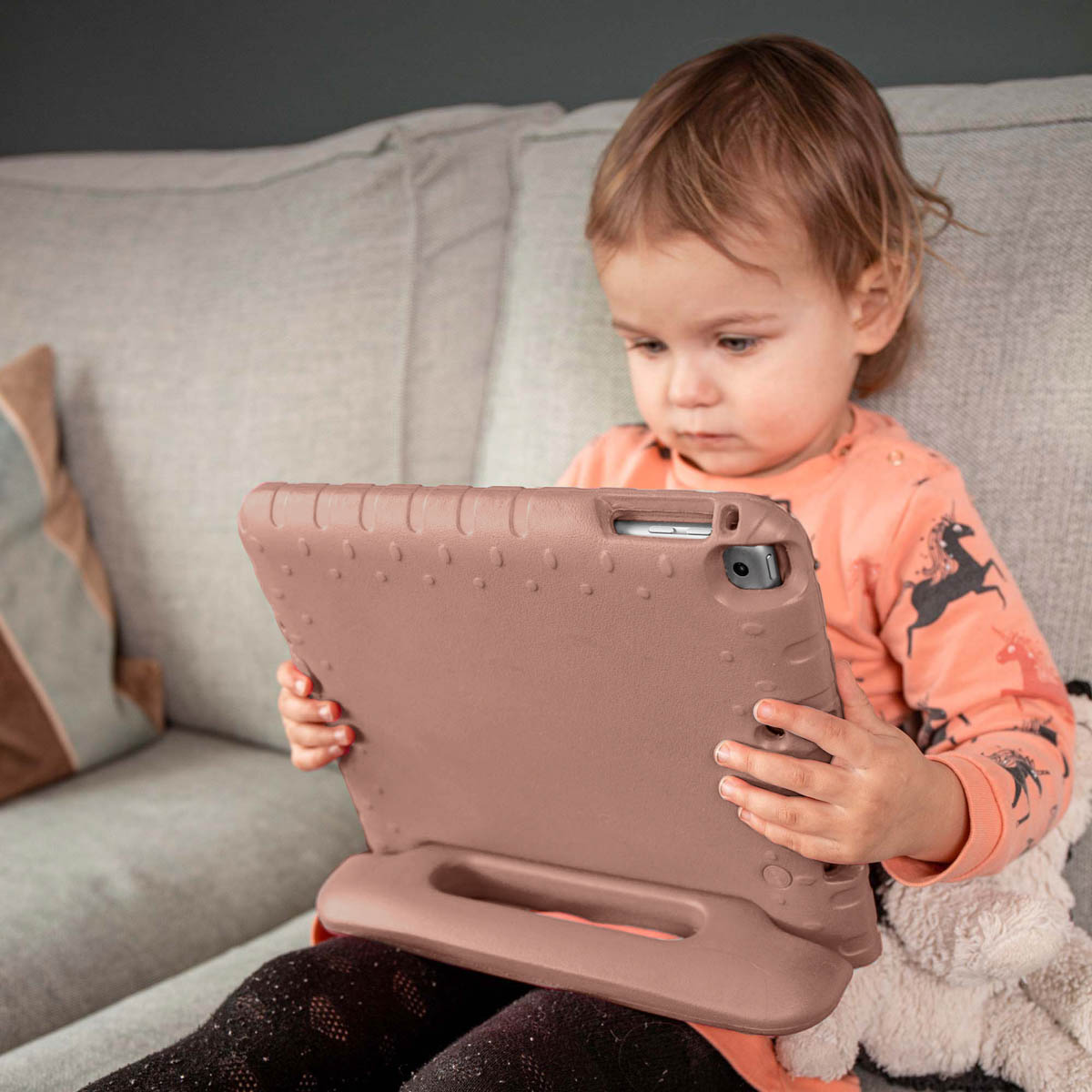 Een kind houdt een bruine tablet in handen.