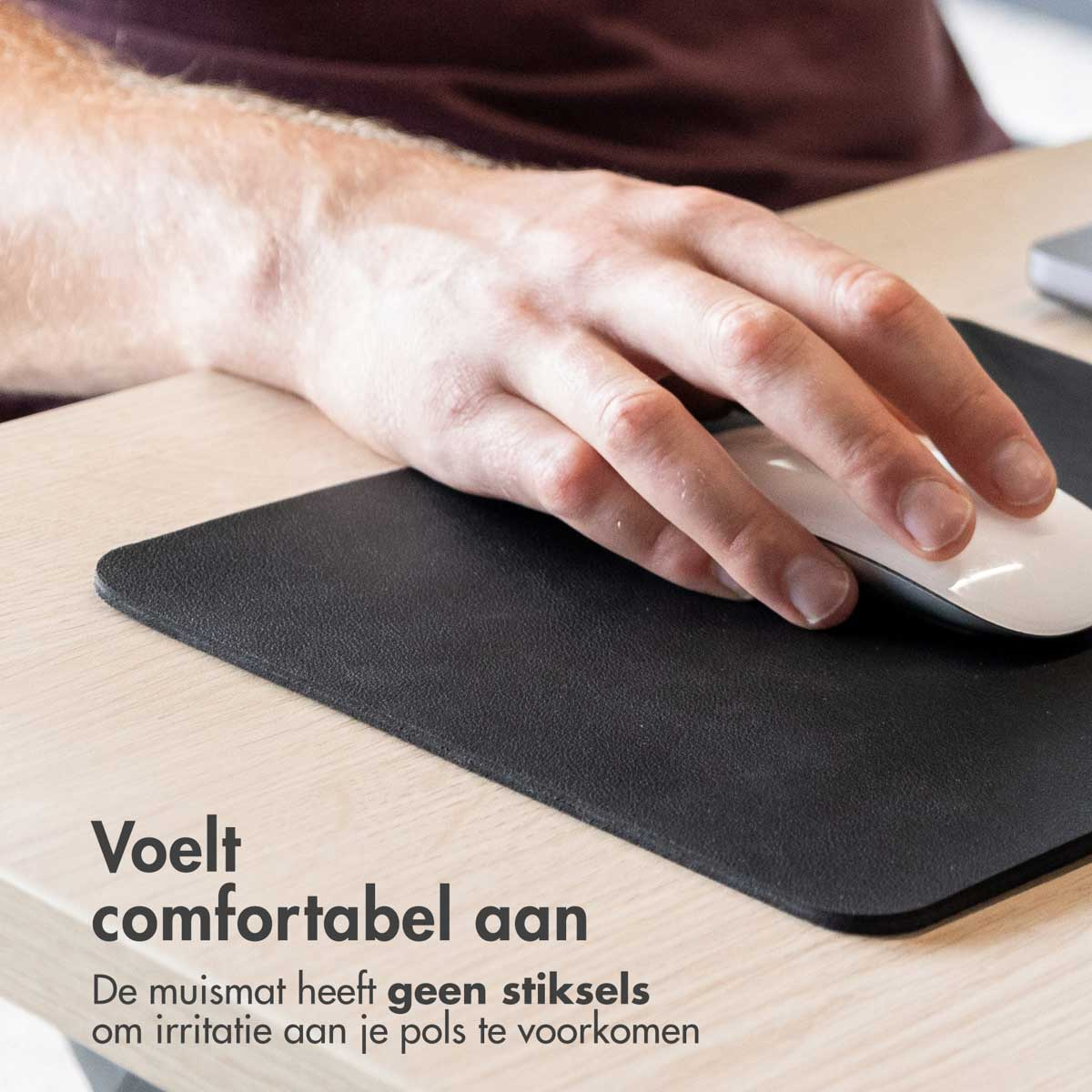 A hand uses a white mouse on a black mousepad.