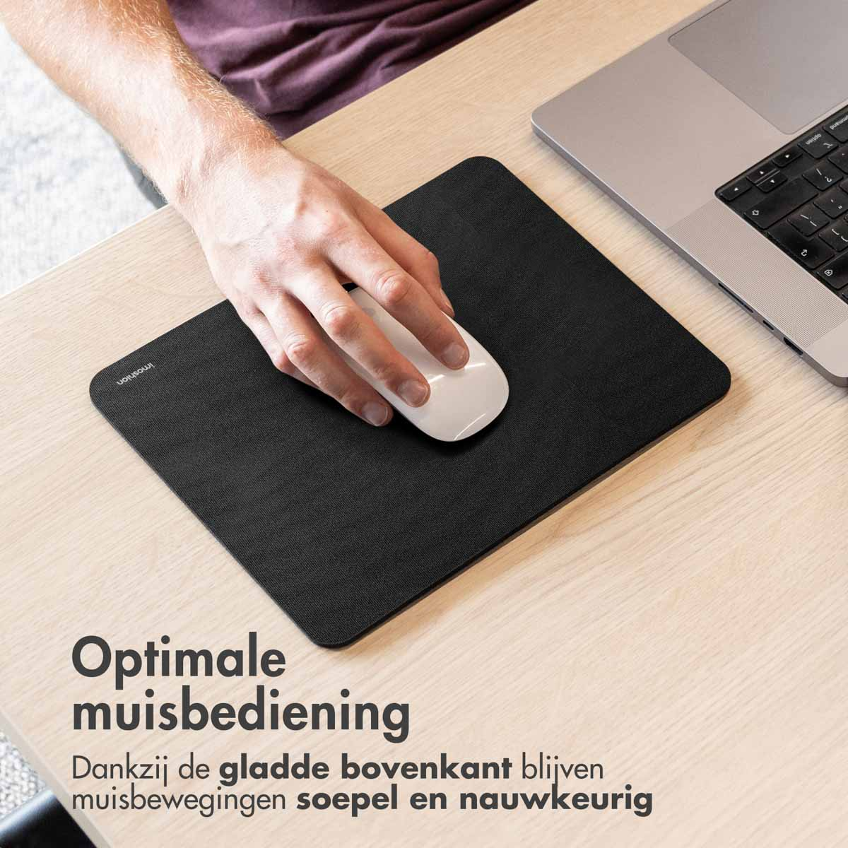 A hand uses a white mouse on a black mousepad.