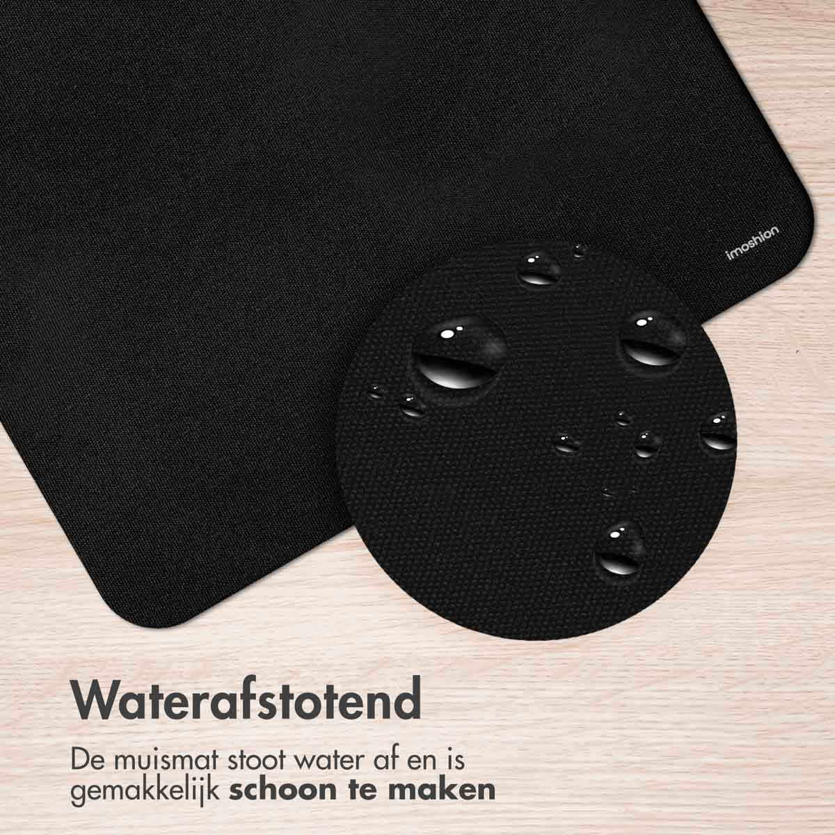 Black mousepad with water droplets on it. The mousepad is on a white surface.