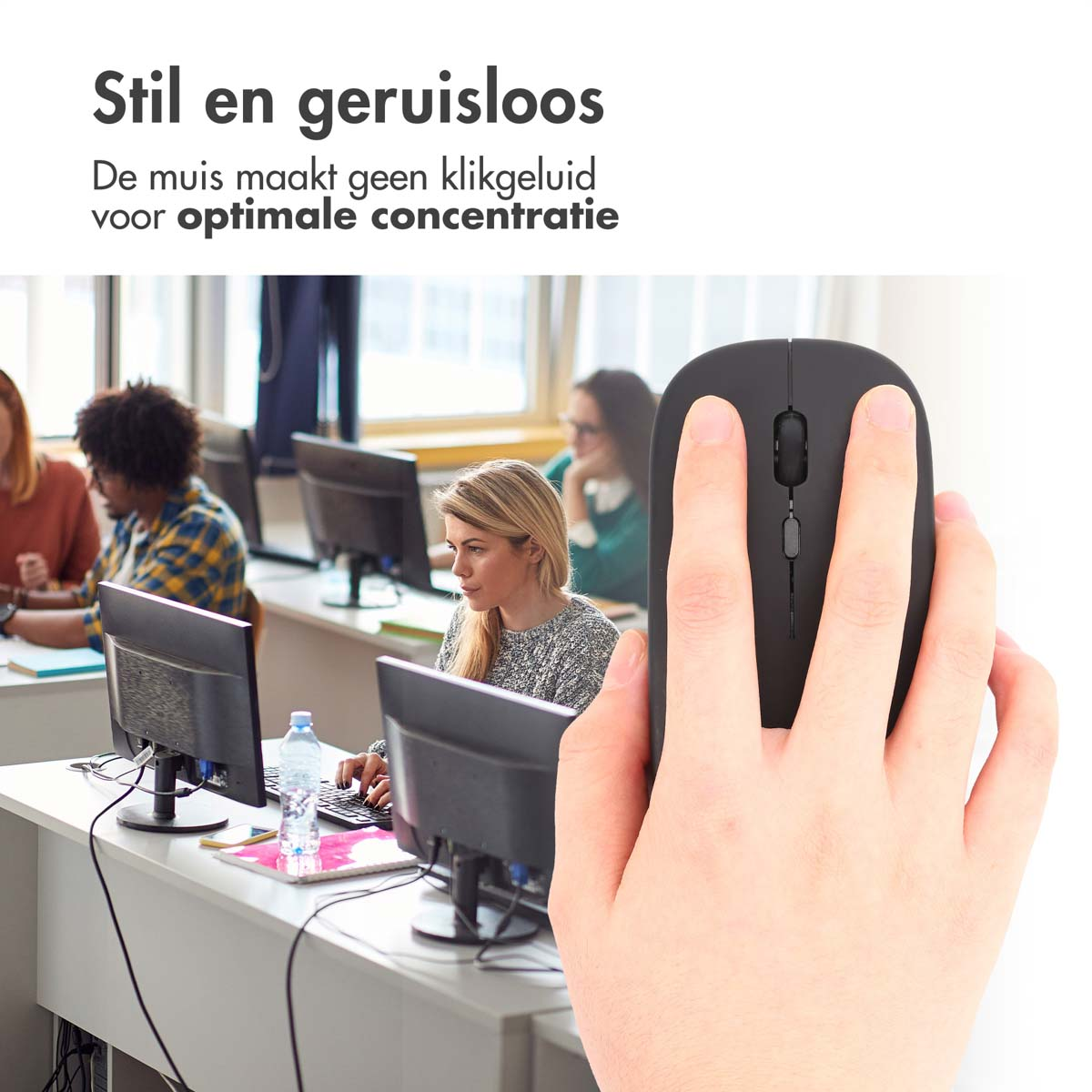 A hand holding a black mouse in front of a group of people in an office.