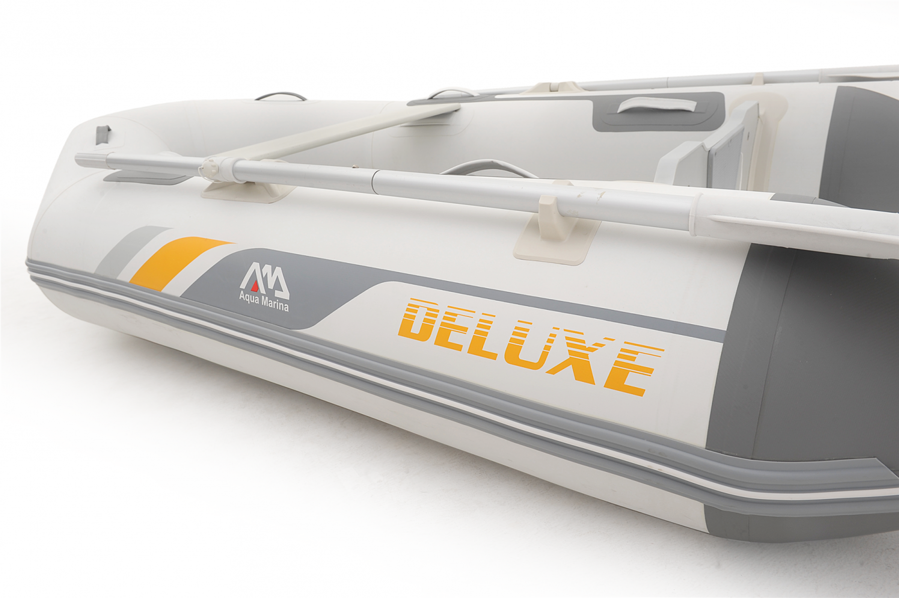 Weißes und graues Schlauchboot mit der Aufschrift „DELUXE“ und Paddeln, auf weißem Hintergrund.