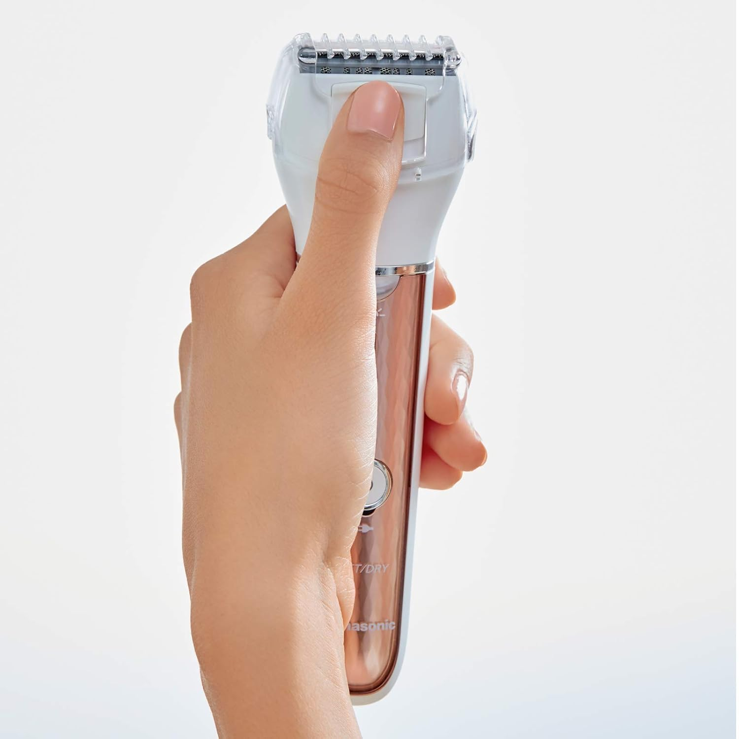 Eine Hand hält einen weißen und kupferfarbenen Elektrorasierer vor weißem Hintergrund.