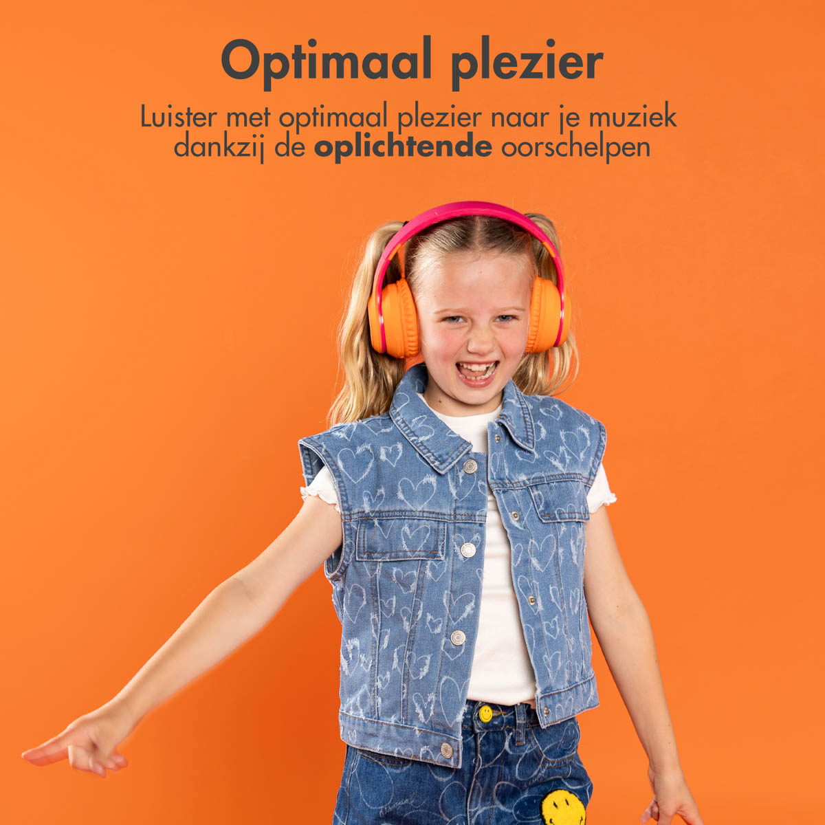 Een meisje met een oranje koptelefoon en een spijkerjasje lacht op een oranje achtergrond.
