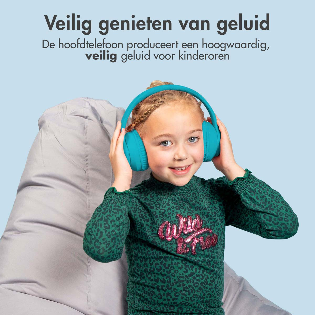 Jong meisje met een turquoise koptelefoon, lachend op een grijze zitzak.