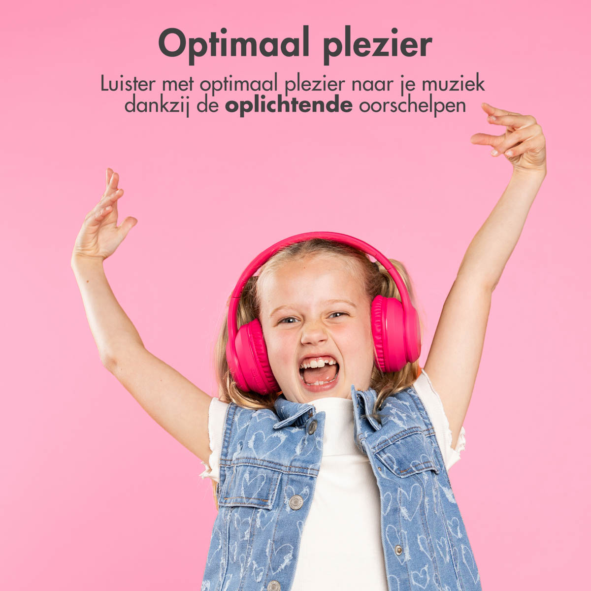 Meisje met roze koptelefoon en armen omhoog, lachend. Roze achtergrond. Spijkerjasje.