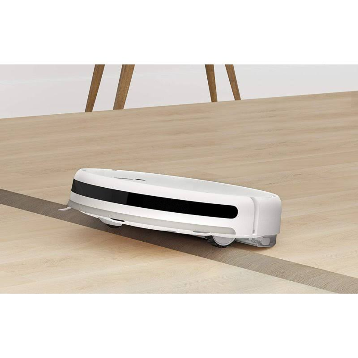 Una aspiradora robot blanca sobre un suelo de madera. Es redonda y tiene una franja negra.