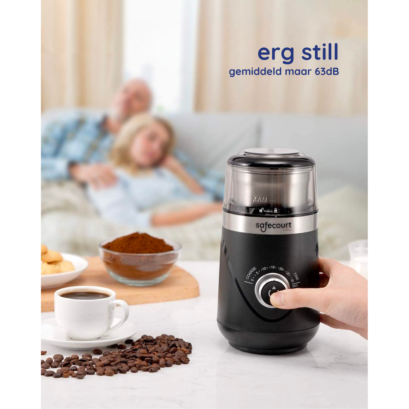 Black coffee grinder and a hand turning a dial. Two people are in the background.
