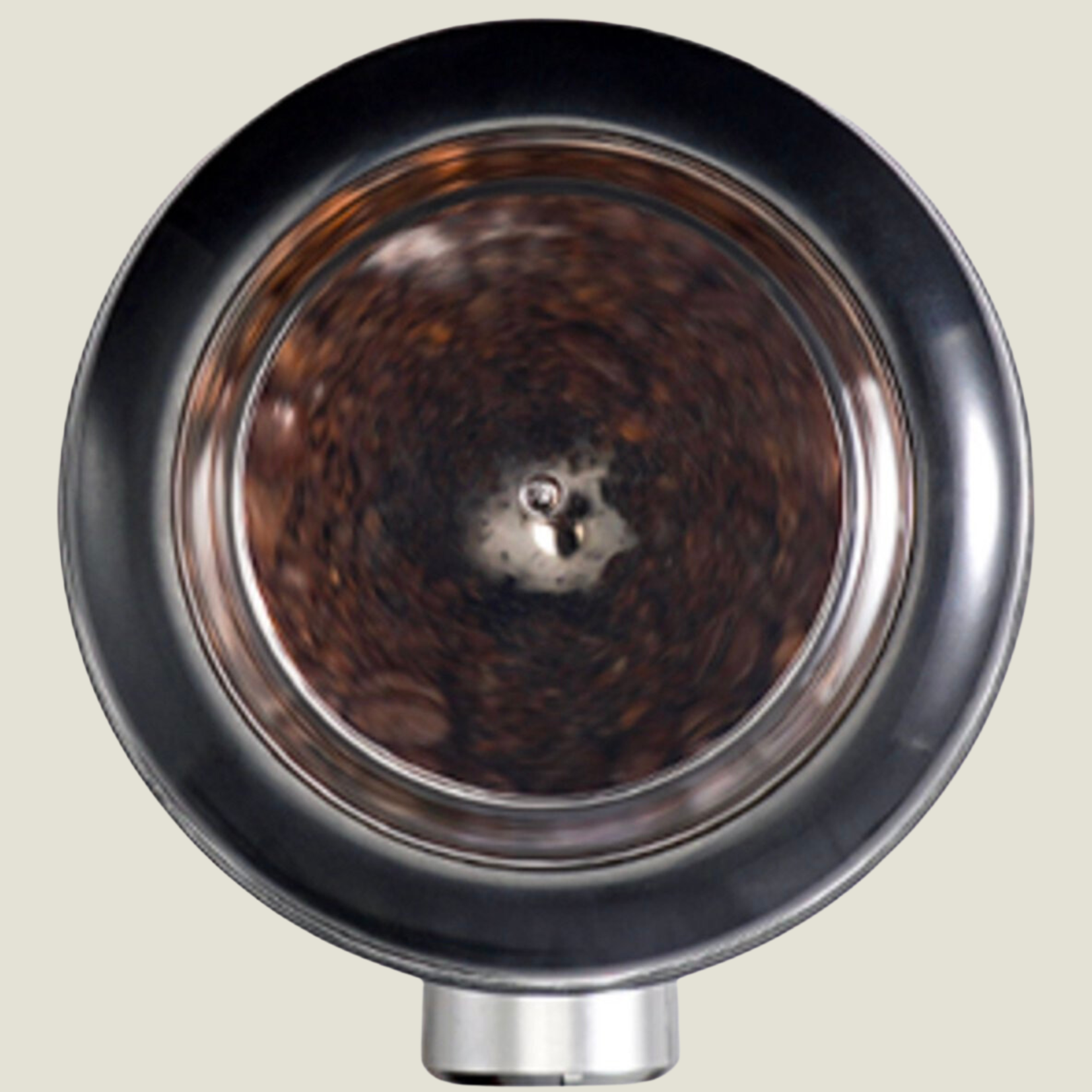 Top view of coffee beans being ground inside a machine. Black and silver machine in the background.