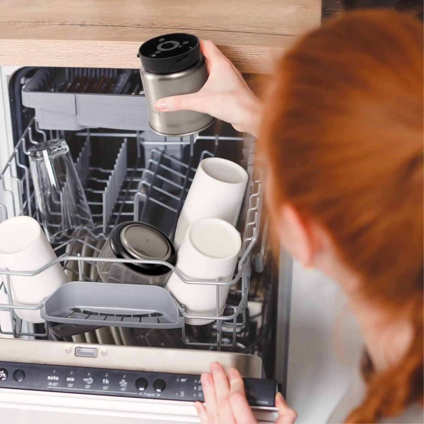 Woman putting a dishwasher part into a dishwasher with clean dishes inside. 