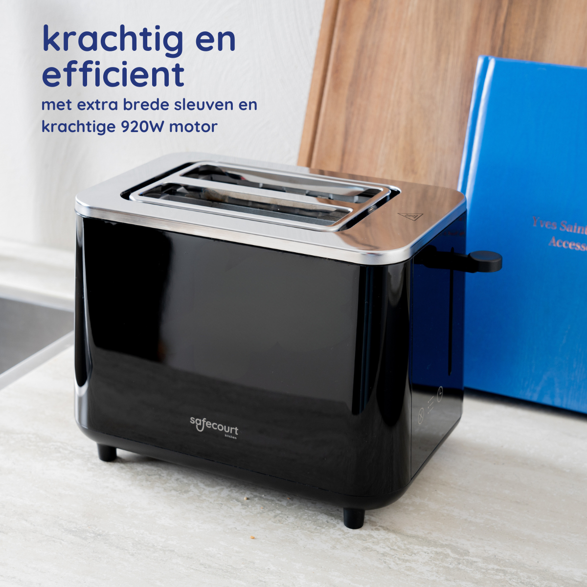 Zwarte en zilveren broodrooster op een aanrecht. Een houten plank en boek staan rechts. Keuken op de achtergrond.