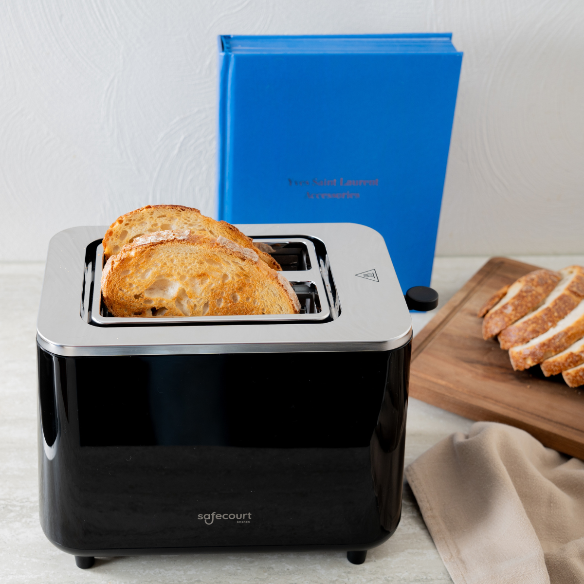 Broodrooster met twee sneetjes brood erin, een boek en een houten plank ernaast.