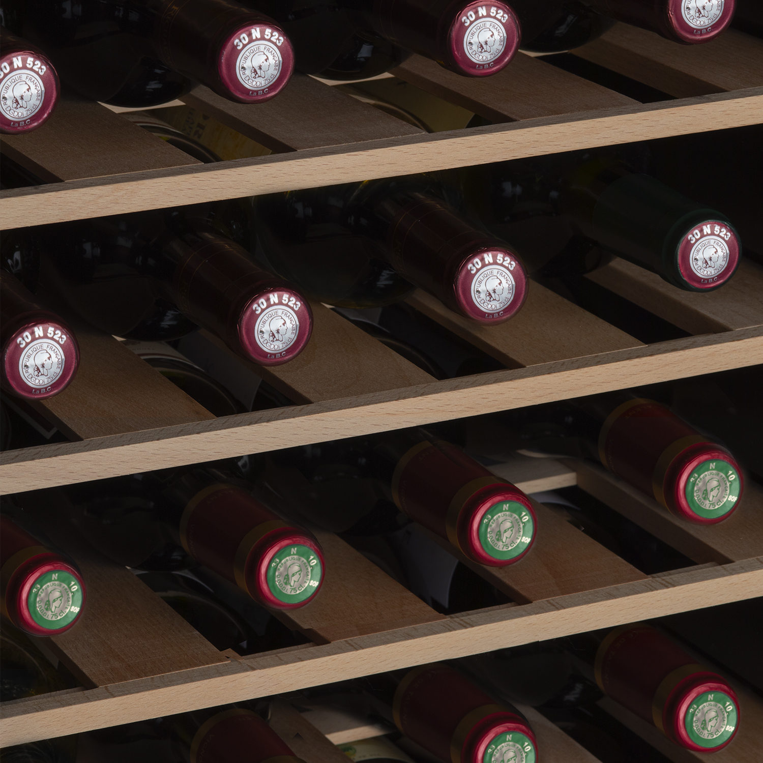 Weinflaschen auf Holzregalen. Die Flaschen haben rote Kappen und Etiketten, in einem Weinregal.