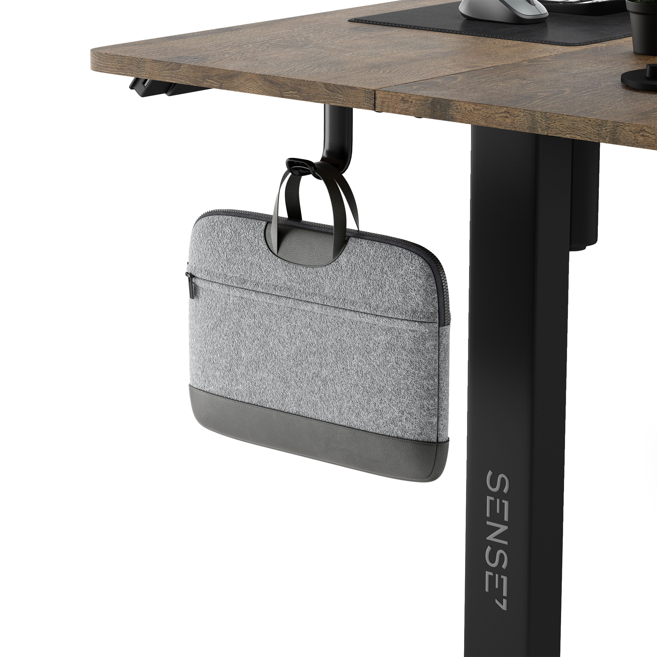 Una custodia grigia per laptop appesa sotto una scrivania in legno con una gamba nera.