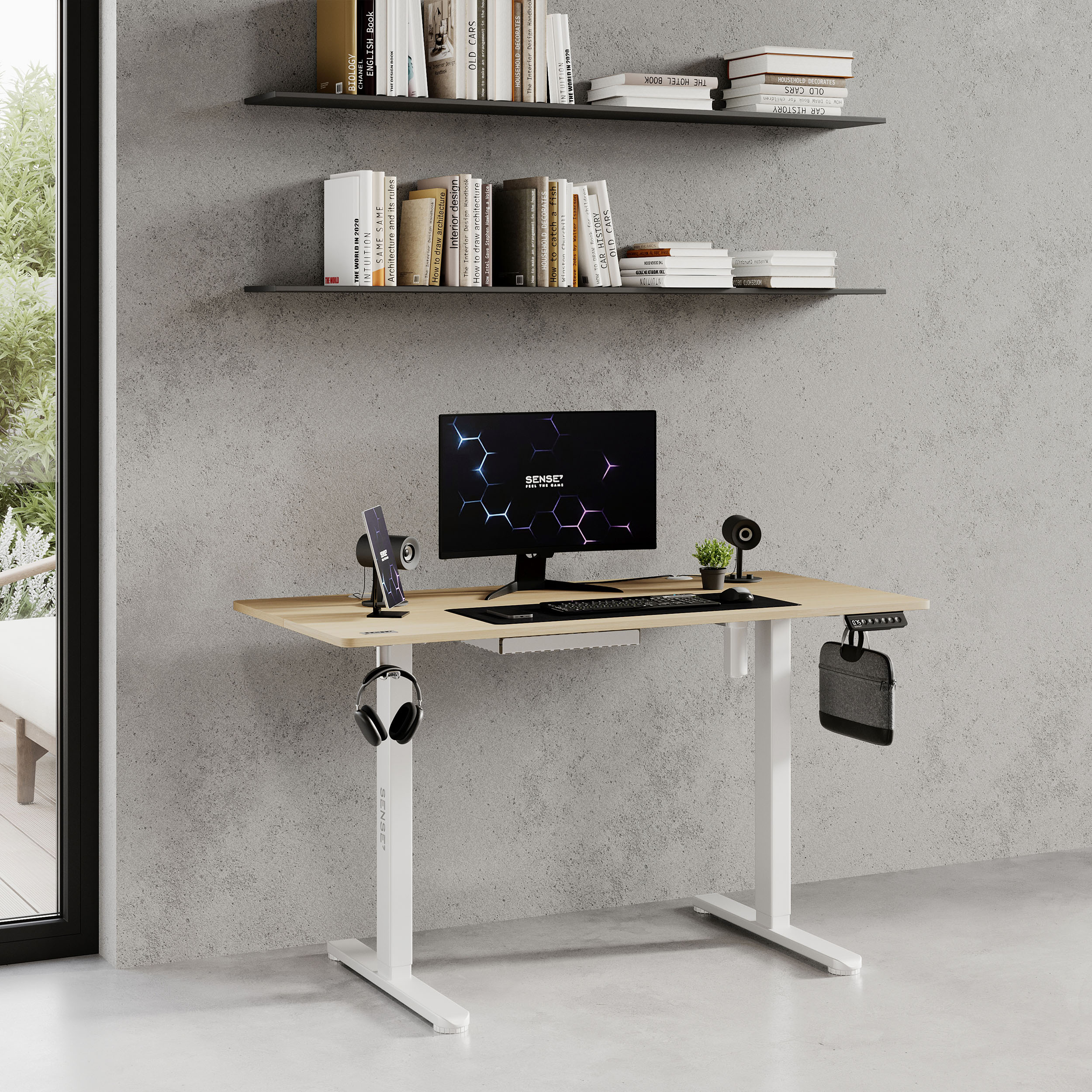 Una scrivania regolabile in altezza con monitor, cuffie e altri accessori tecnologici.