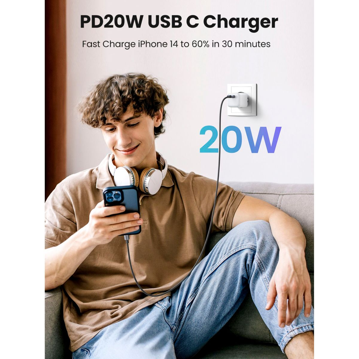 Mężczyzna używa telefonu podczas ładowania. Ładowarka jest podłączona do ściany. Tekst: PD20W USB C Charger.