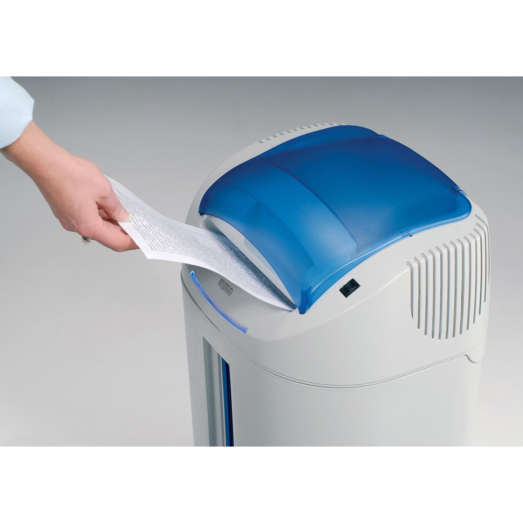 Mano inserisce carta in distruggidocumenti bianco e blu.