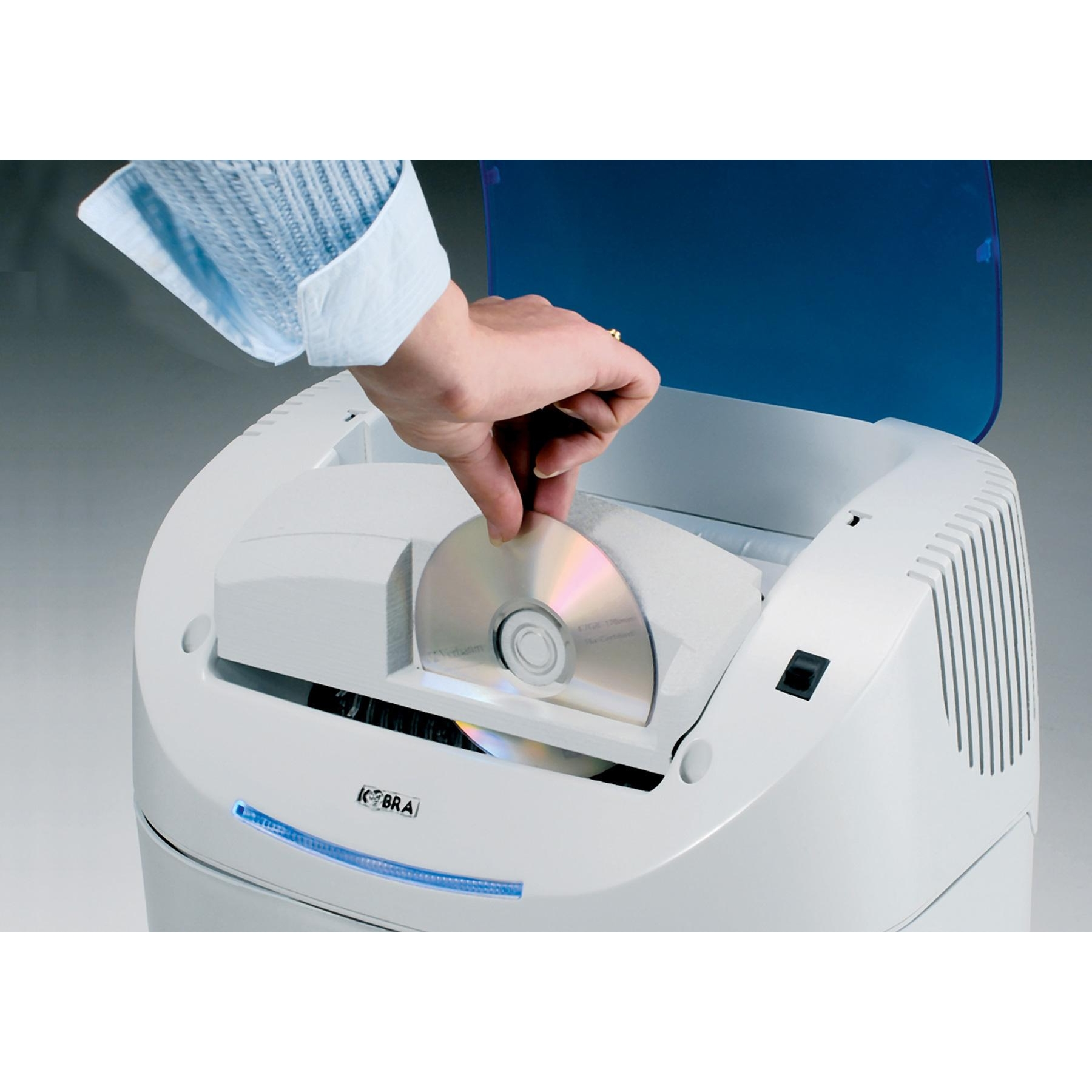 Una persona che inserisce un CD in un trituratore di CD bianco. La macchina ha una copertura blu.