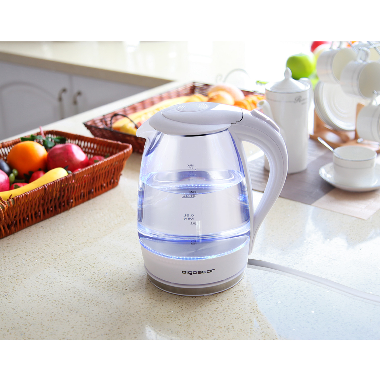 Elektrischer Wasserkocher aus klarem Glas. Weißer Sockel und Griff. Wasser innen. Küchenhintergrund.