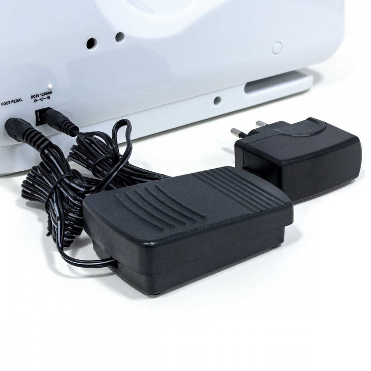 Zbliżenie białego urządzenia z pedałem nożnym i połączeniami kabla zasilającego.