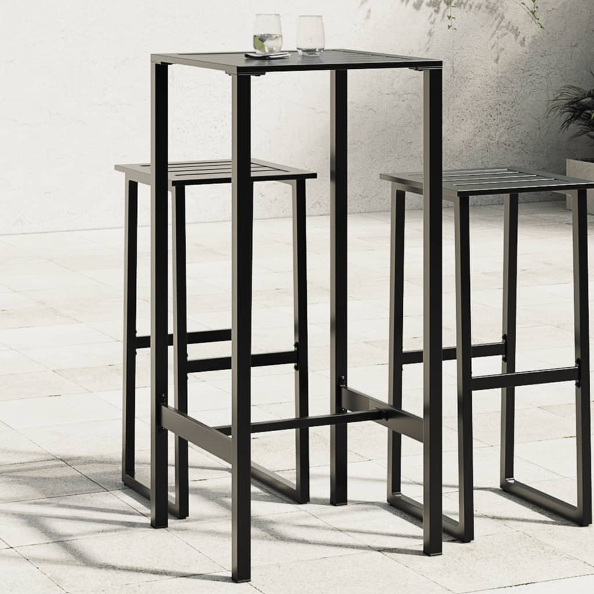 Schwarzes Metall-Outdoor-Bar-Set mit einem quadratischen Tisch und zwei Hockern. Auf einer gefliesten Terrasse platziert.