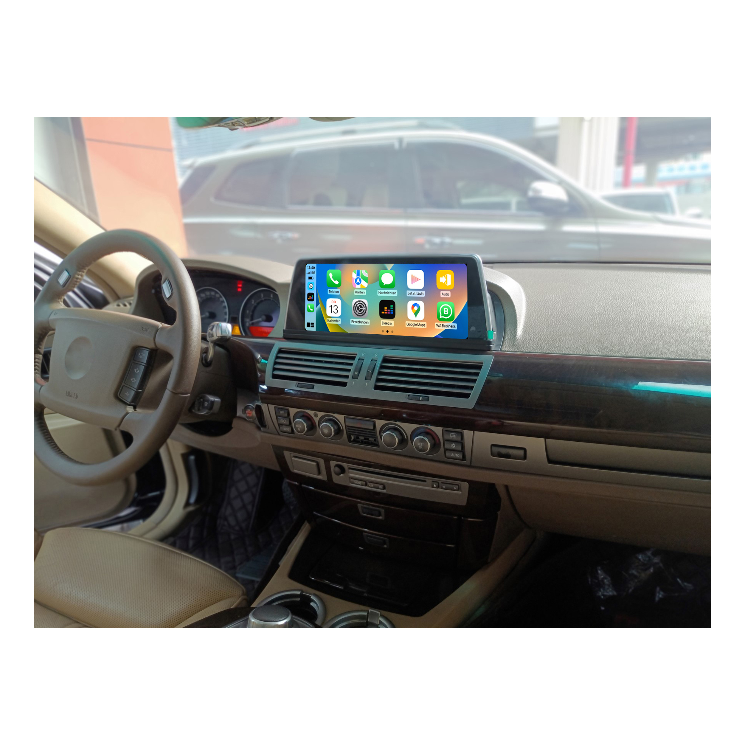 Autointerieur, Armaturenbrett mit Bildschirm, der Apps anzeigt. Lenkrad und Fahrzeugaußenseite im Hintergrund sichtbar.