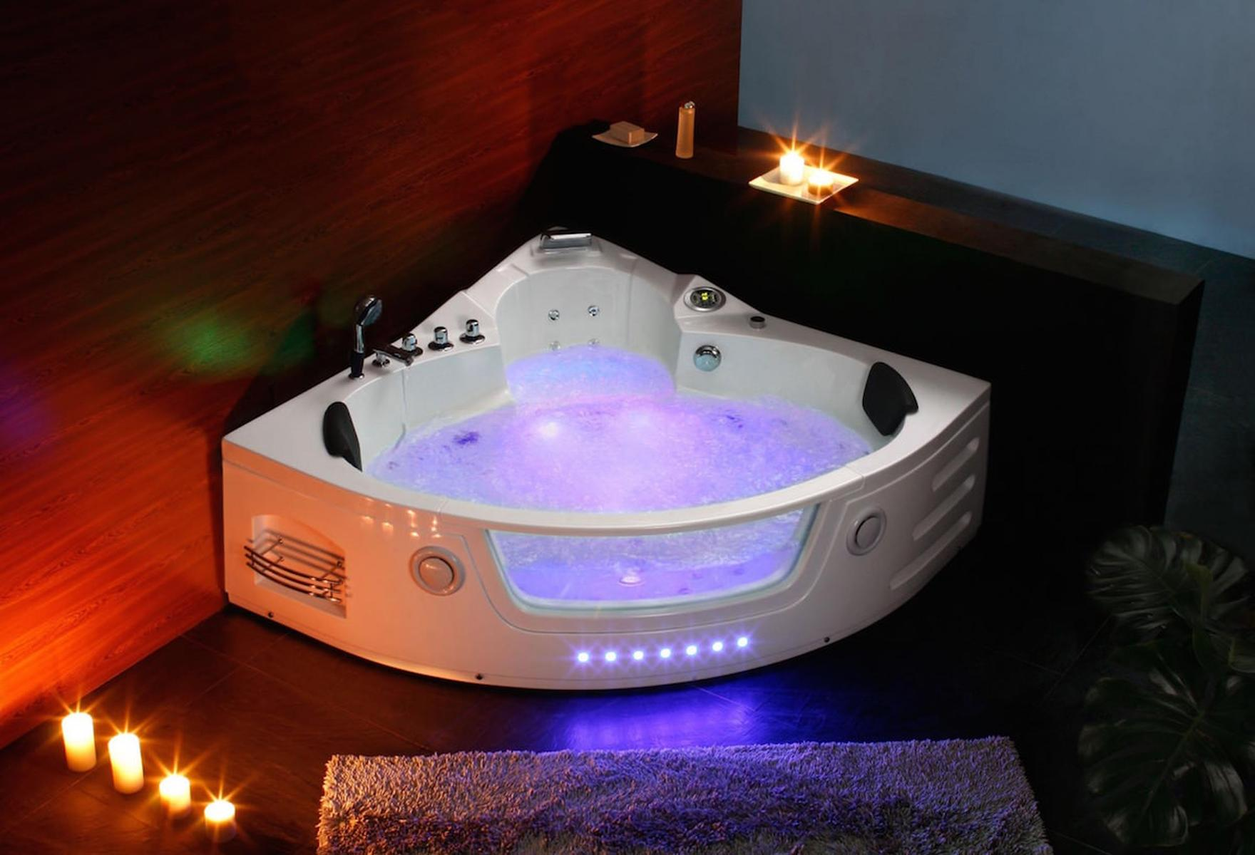 Weißes Eck-Jacuzzi mit lila Lichtern, Kerzen und einer dunklen Holzwand.
