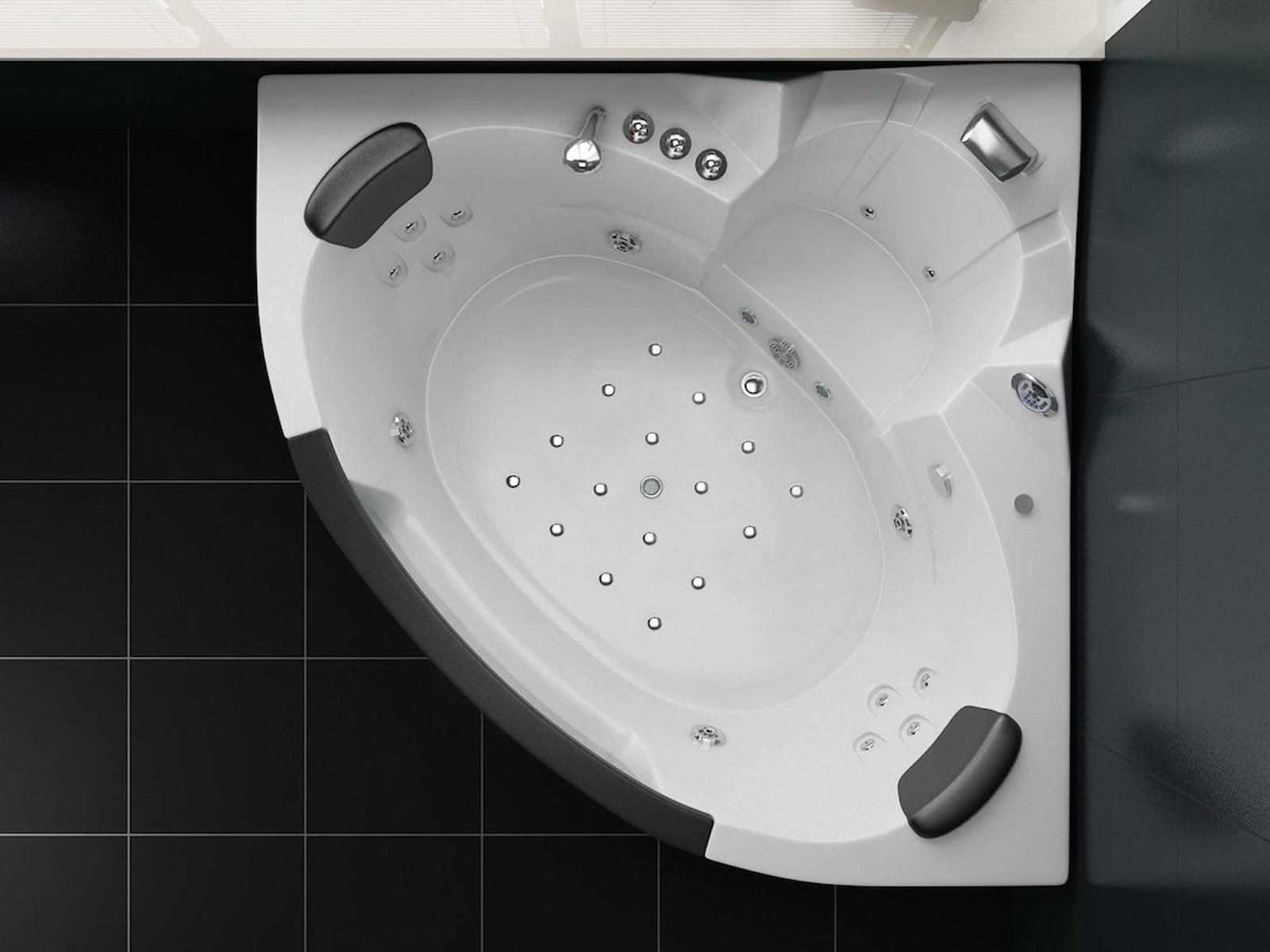 Ein weißes, eckförmiges Jacuzzi. Das Jacuzzi hat mehrere Düsen und Kopfstützen. Schwarze Fliesen umgeben das Jacuzzi.