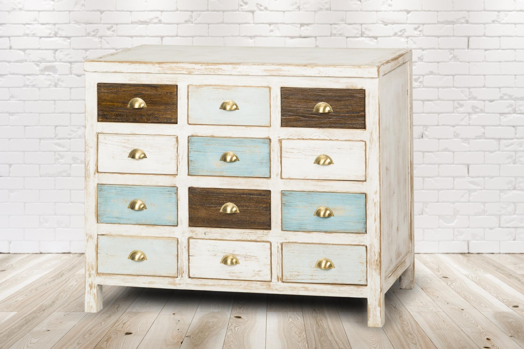 Ein weißer Schrank mit 12 Schubladen. Die Schubladen haben verschiedene Farben und goldene Griffe. Holzfußboden.