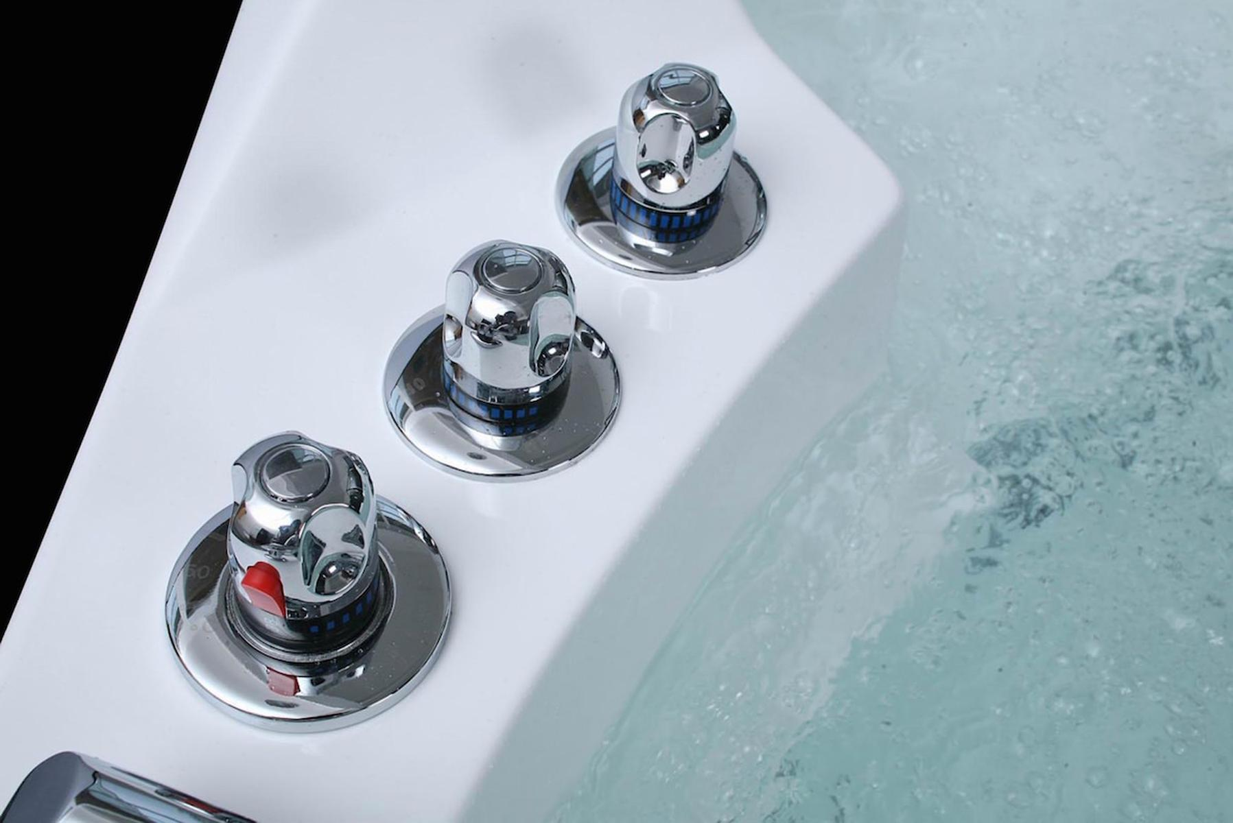Nahaufnahme von drei silbernen Bedienknöpfen auf einer weißen Oberfläche mit Wasser. Die Knöpfe sind beschriftet.