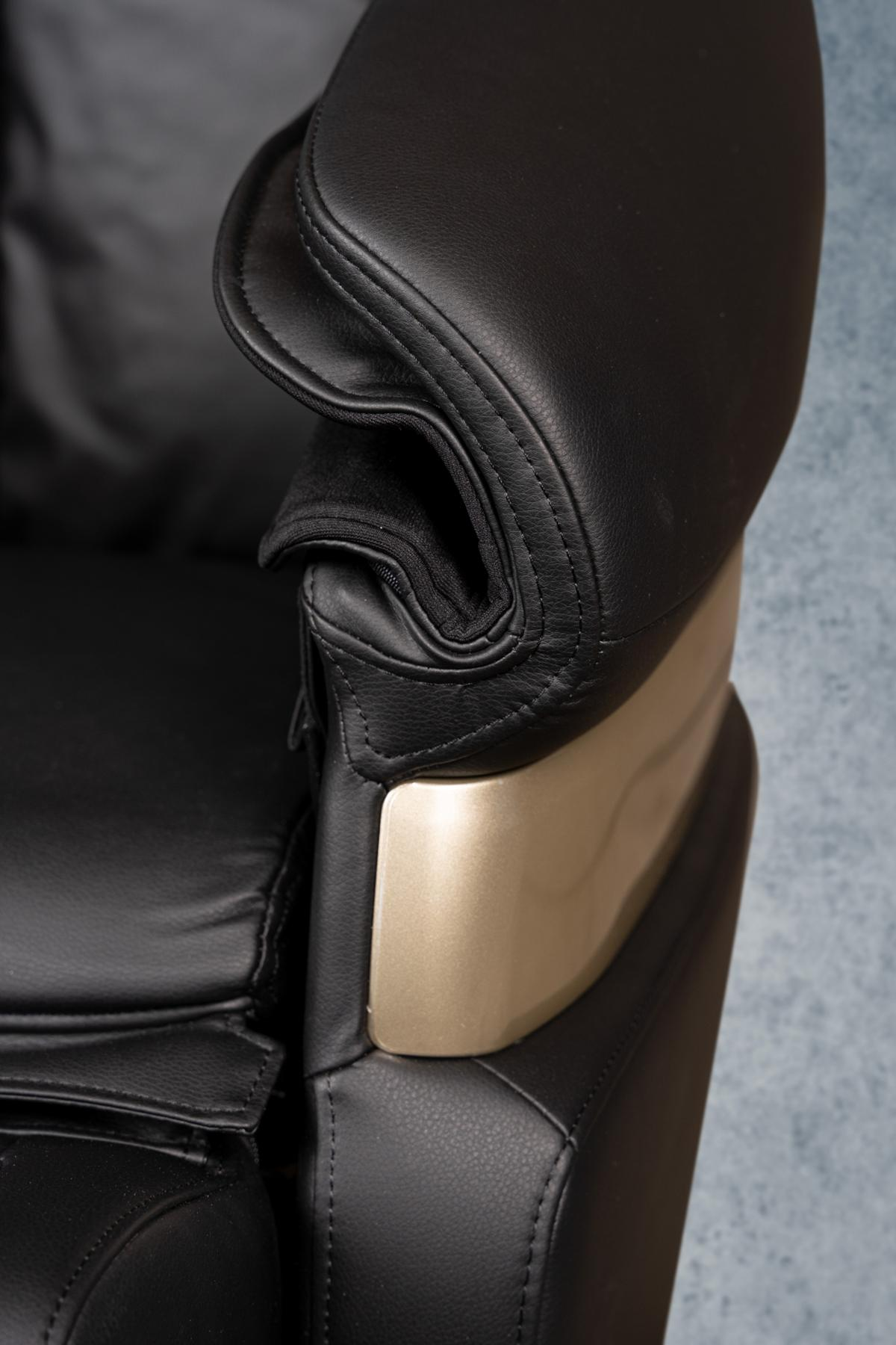 Nahaufnahme einer schwarzen Lederarmlehne eines Massagestuhls mit goldfarbenen Akzenten und detaillierten Nähten.