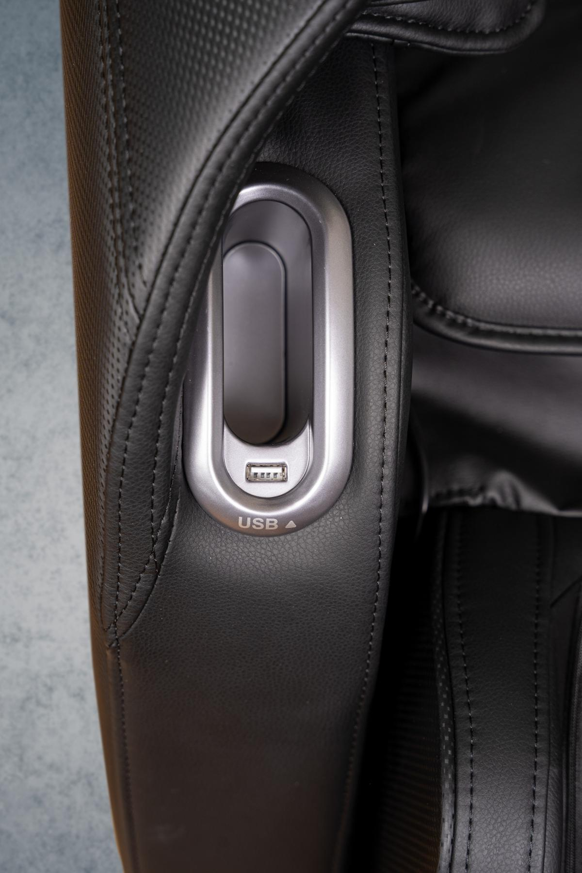 Nahaufnahme eines schwarzen Leder-Massagesessels mit einem USB-Anschluss an der Seite.