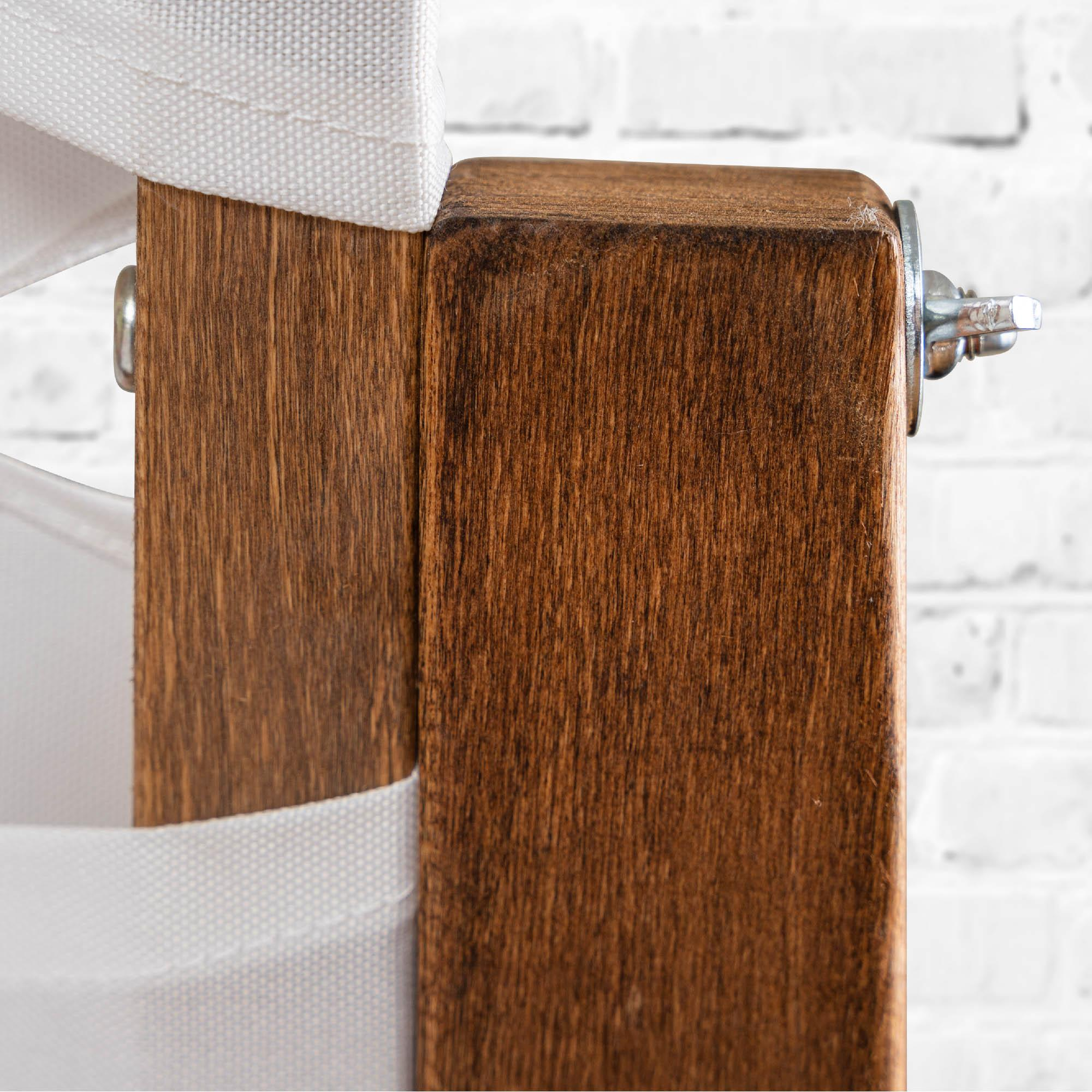 Nahaufnahme einer Holzkonstruktion mit befestigtem weißem Stoff. Schrauben und eine Schraube sind auf der Konstruktion sichtbar.