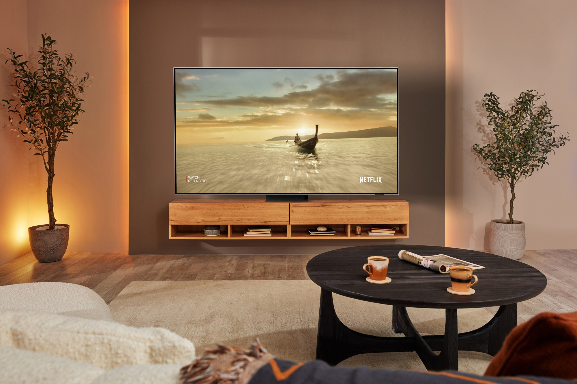 Un soggiorno con una TV che mostra una scena di spiaggia, mobili in legno e decorazioni.