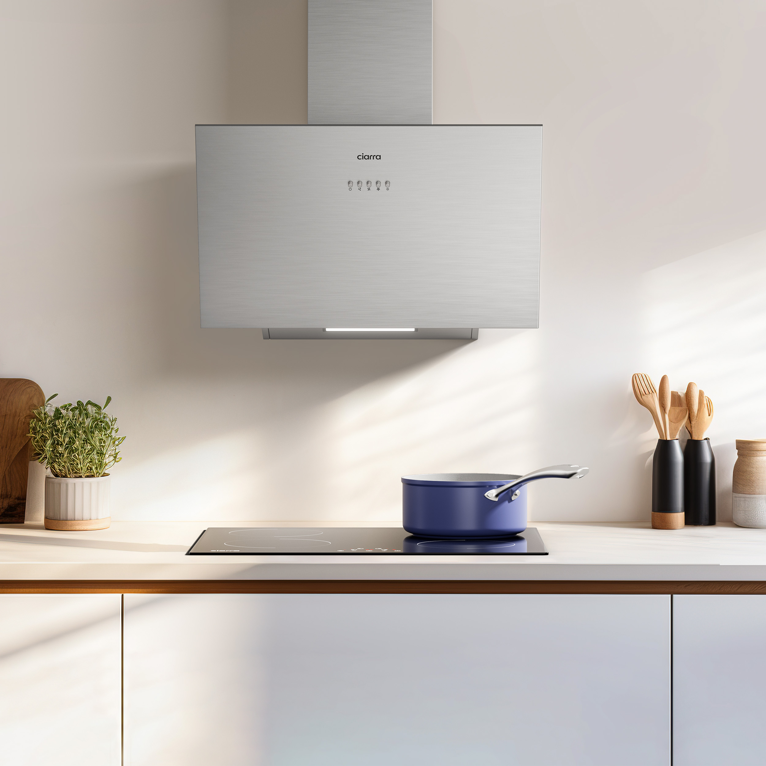A kitchen scene with a range hood, cooktop, and a blue pot.