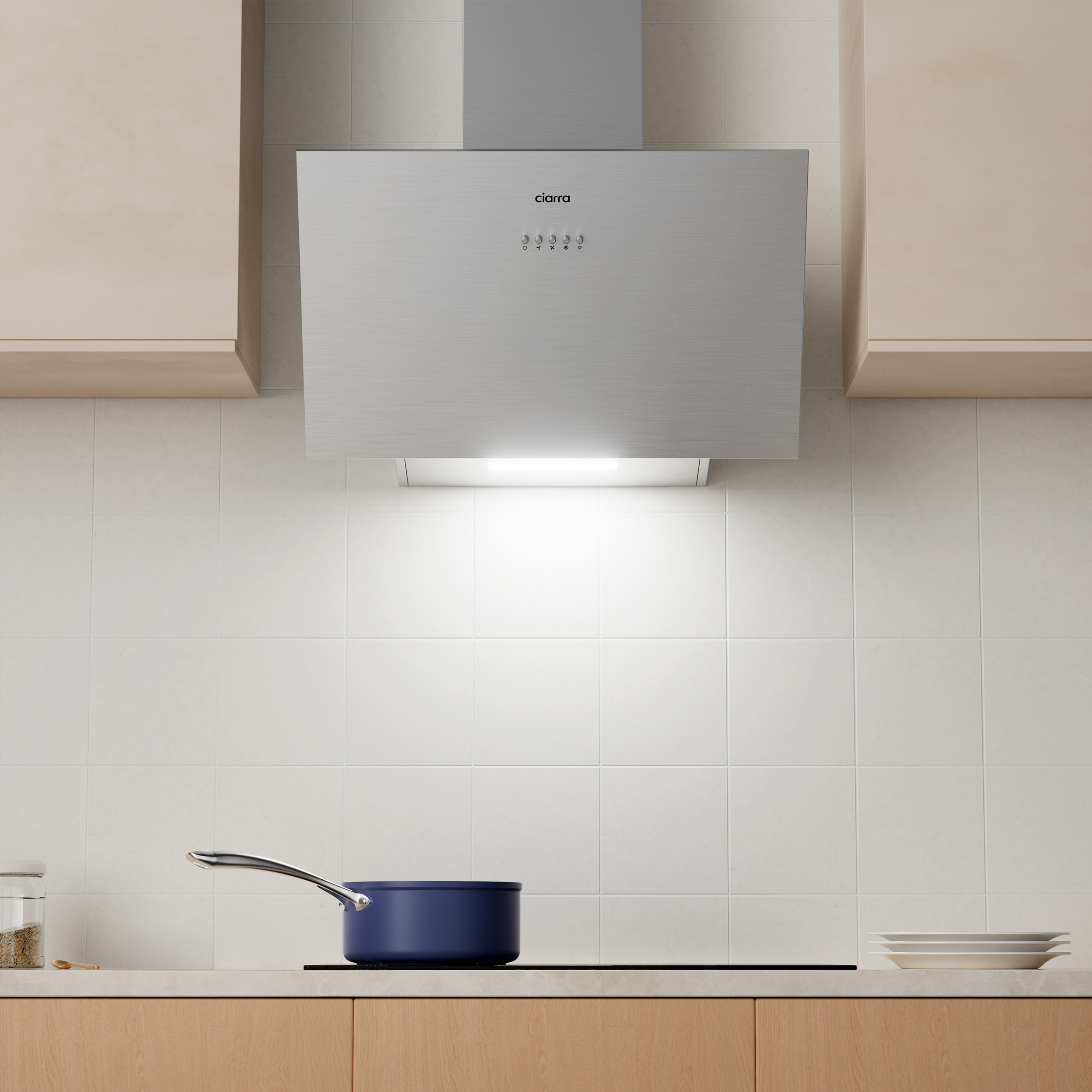 Kitchen scene with a silver range hood. A blue pot sits on the cooktop. Wooden cabinets and white tiles.