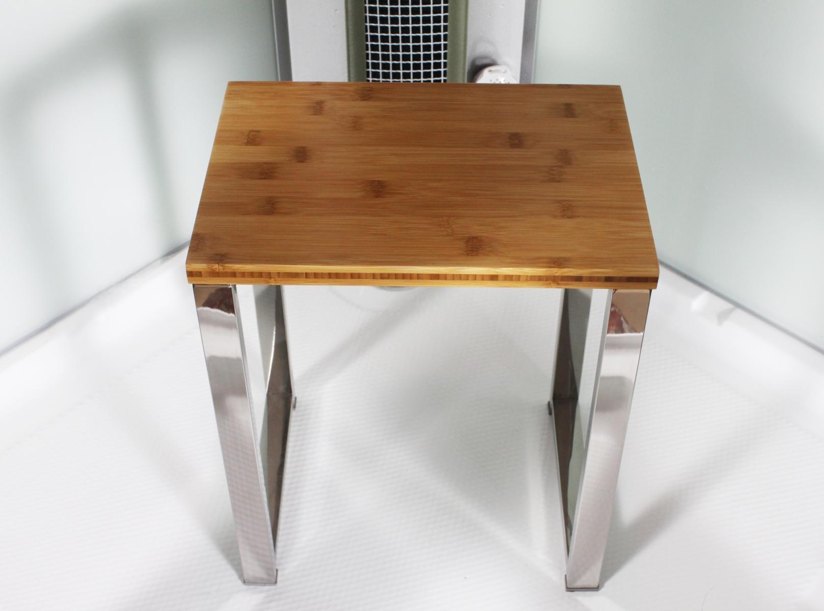 Hocker aus Holz mit Metallbeinen. Braune Oberseite und silberne Beine. Weißer Hintergrund. Der Hocker ist leer.