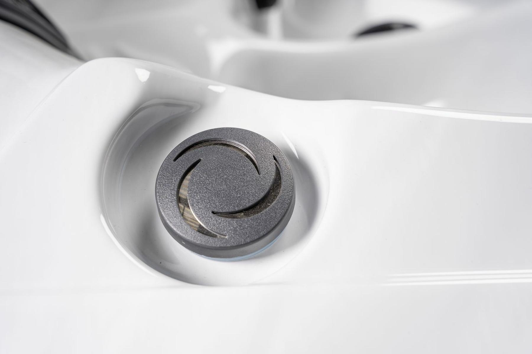 Nahaufnahme einer Whirlpool-Düse auf einem weißen Spa, mit einem dunkelgrauen Zentralelement.