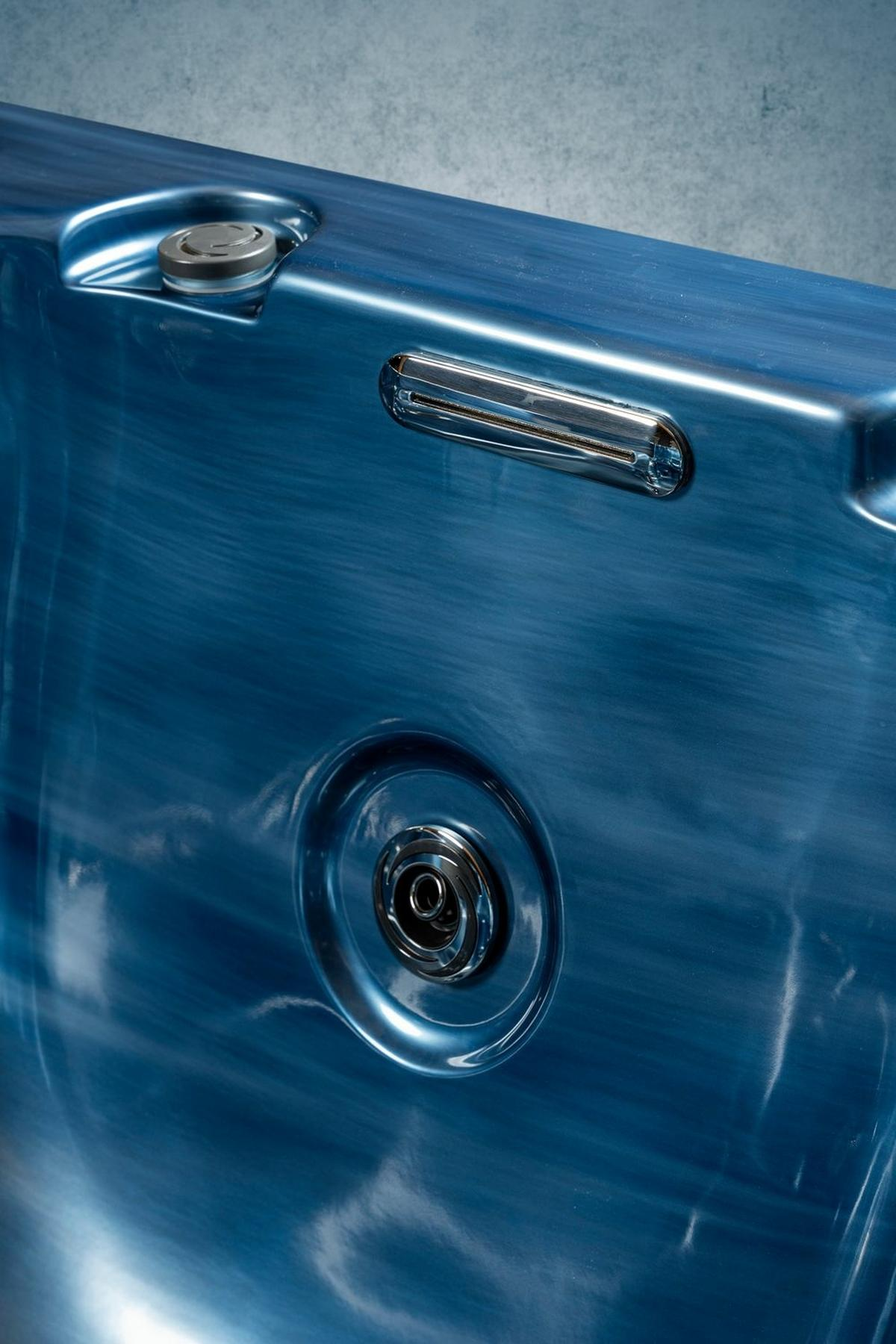 Nahaufnahme eines blauen Whirlpools mit Düsen und Bedienfeld, grauer strukturierter Hintergrund.
